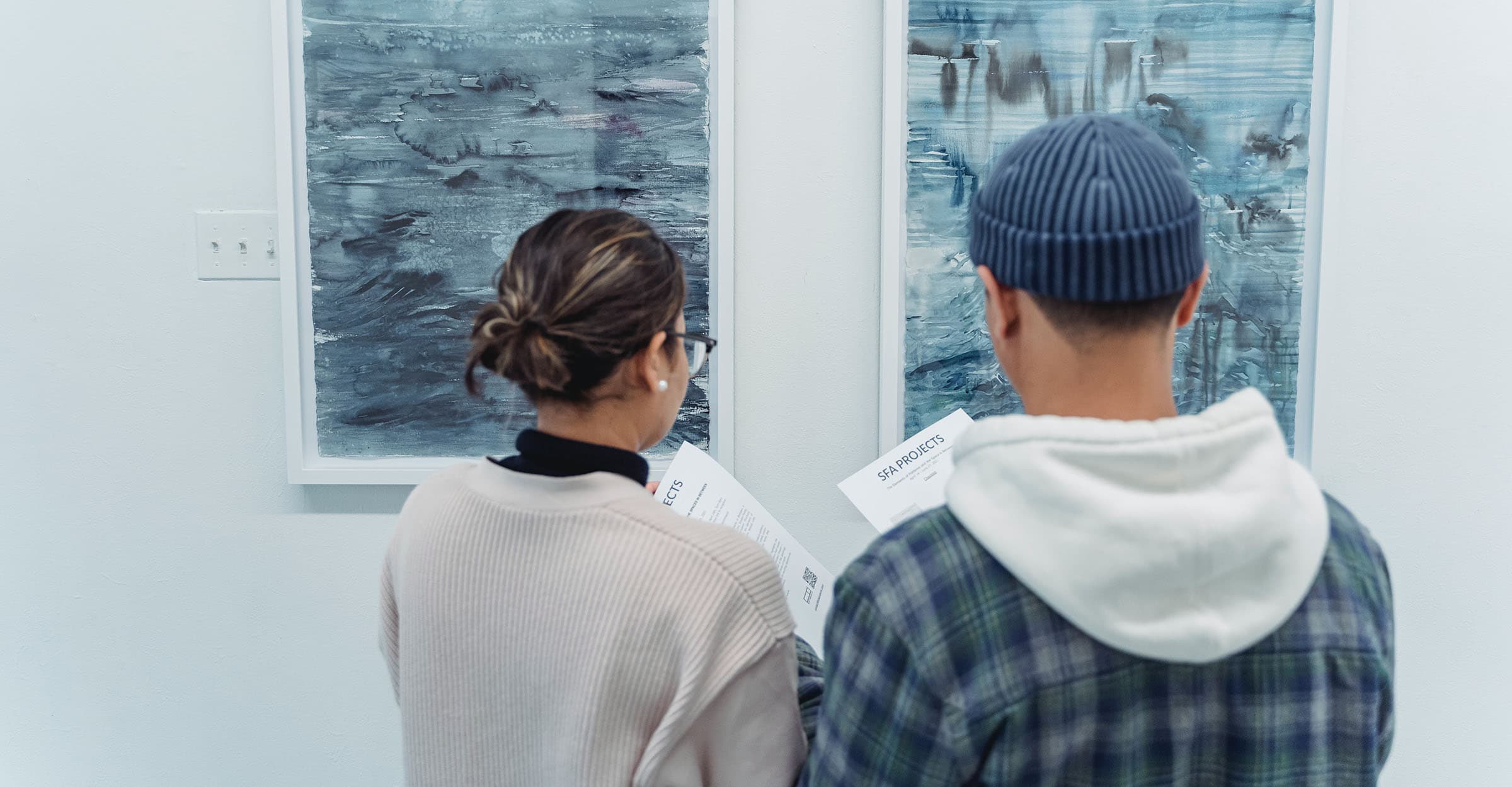 Back View of Man and Woman Standing near the Abstract Paintings Hanged on the Wall