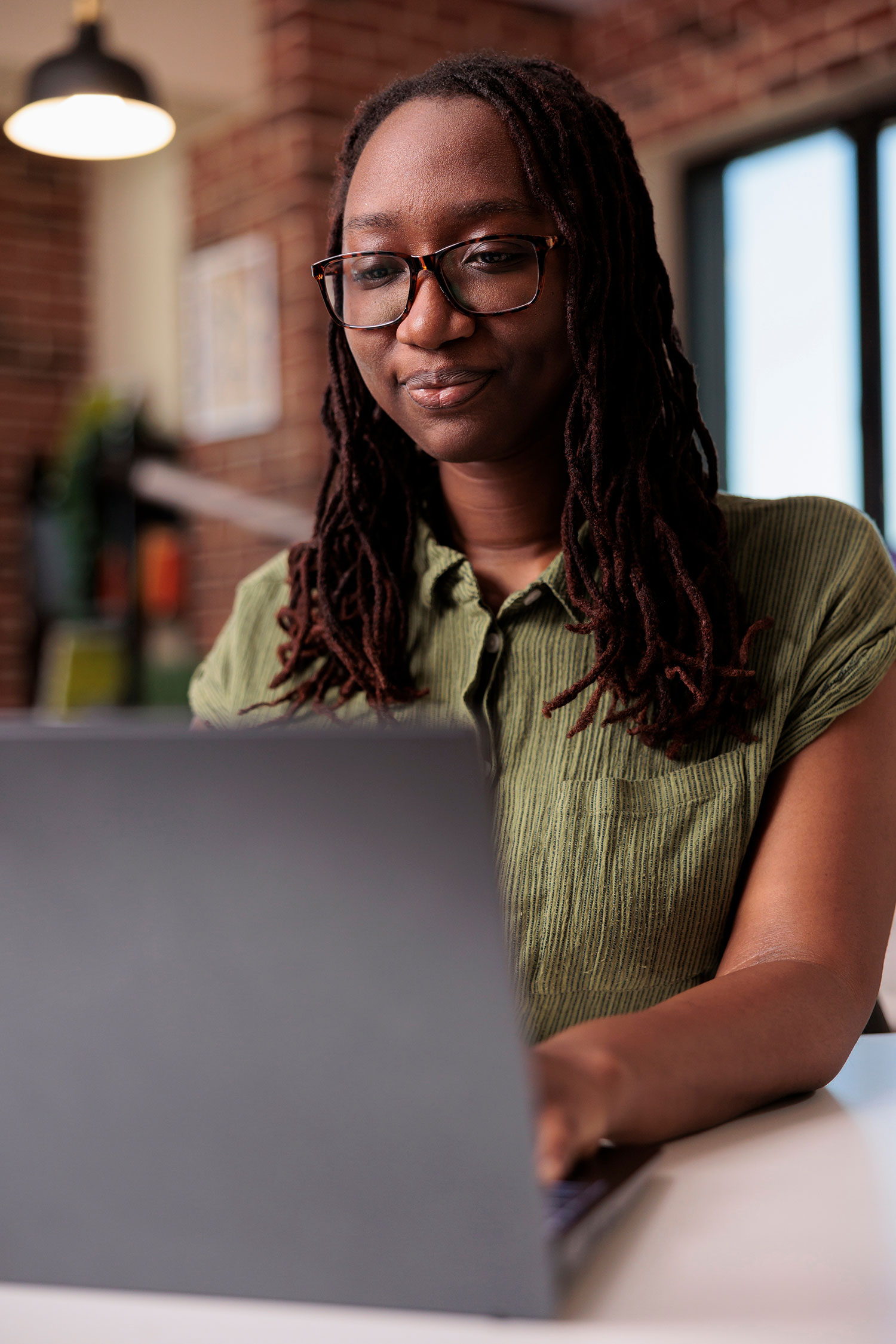 Focused african american entrepreneur working from home typing and looking at laptop screen in home living room. Portrait of freelancer doing remote work on portable computer at desk.