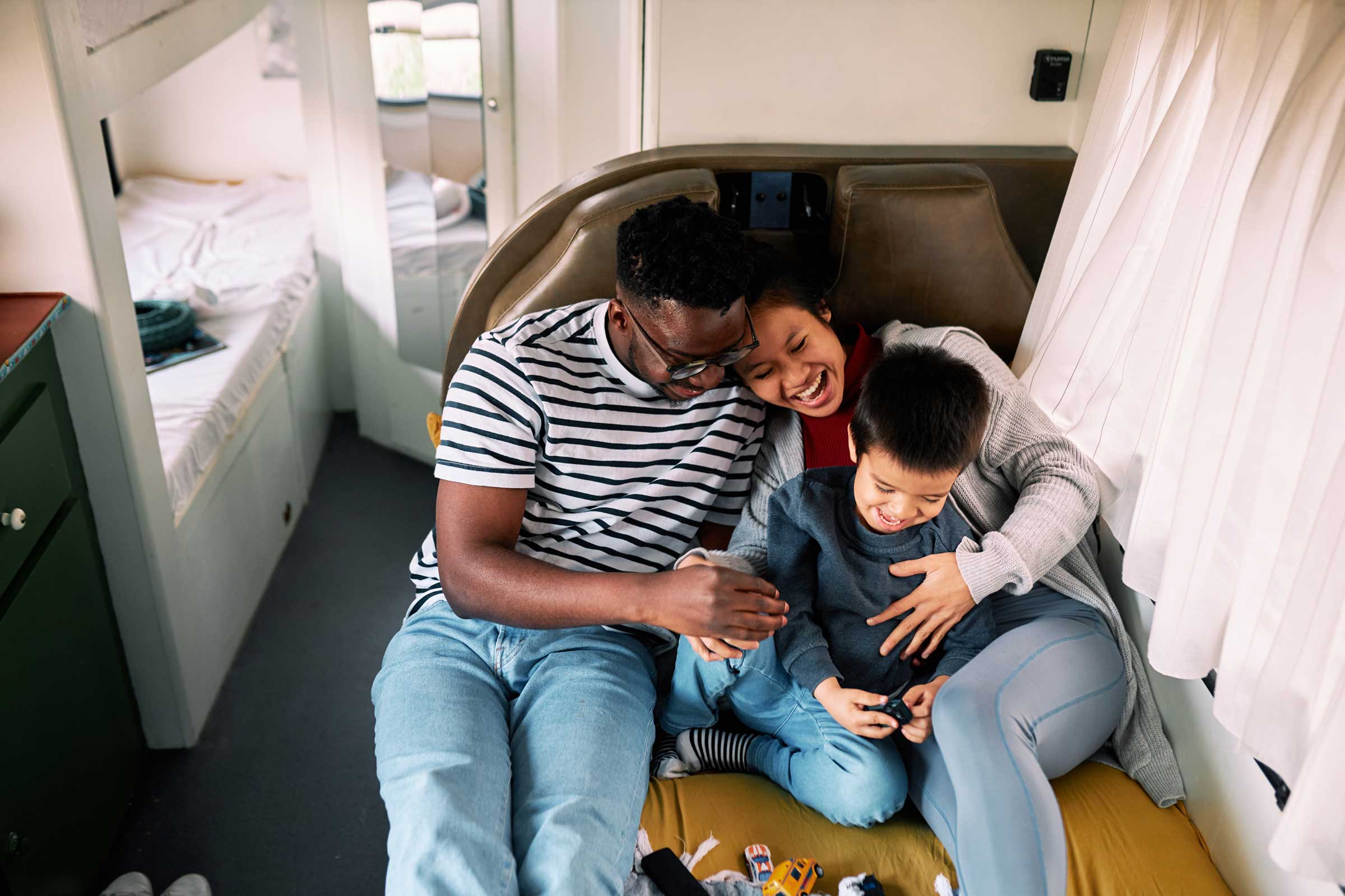 Happy multiracial family of three tickles and cuddles in the motor home