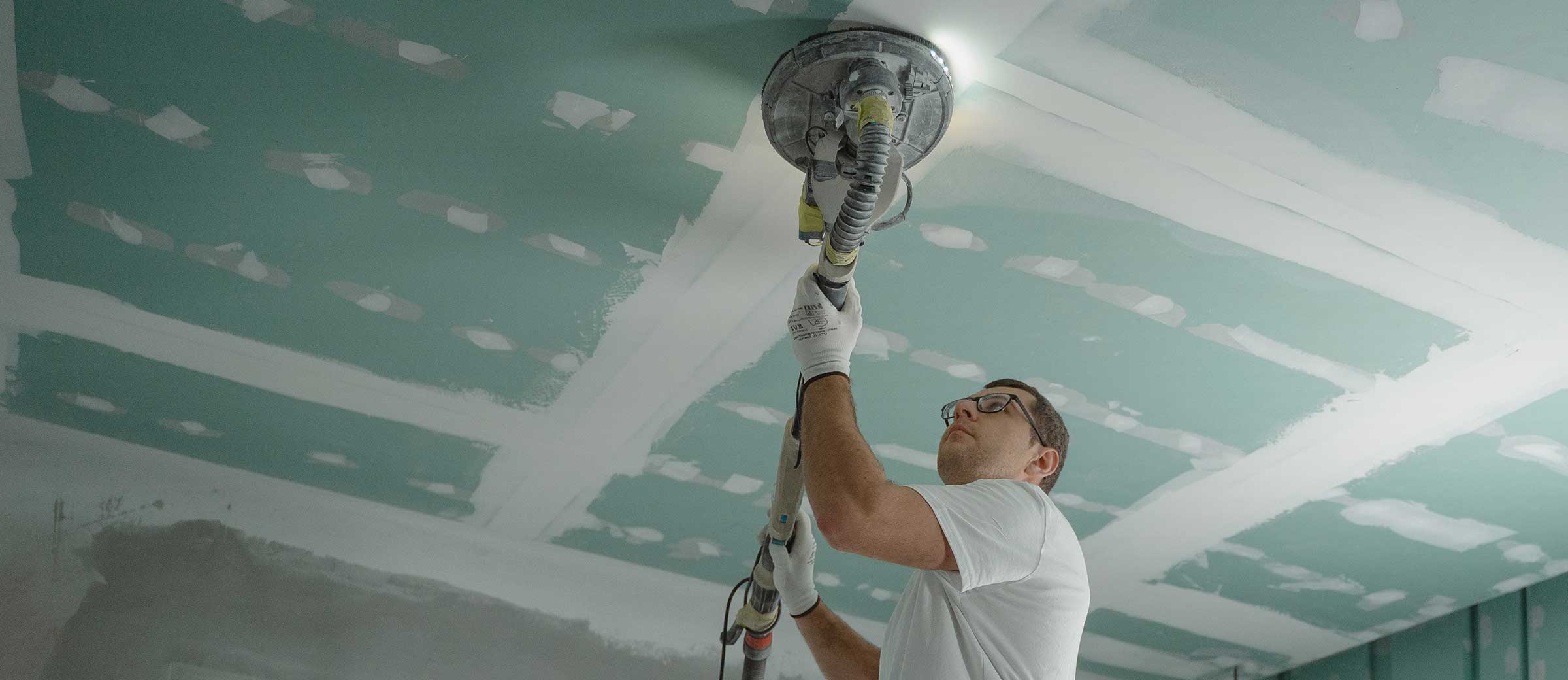 Worker removes popcorn ceiling with sander